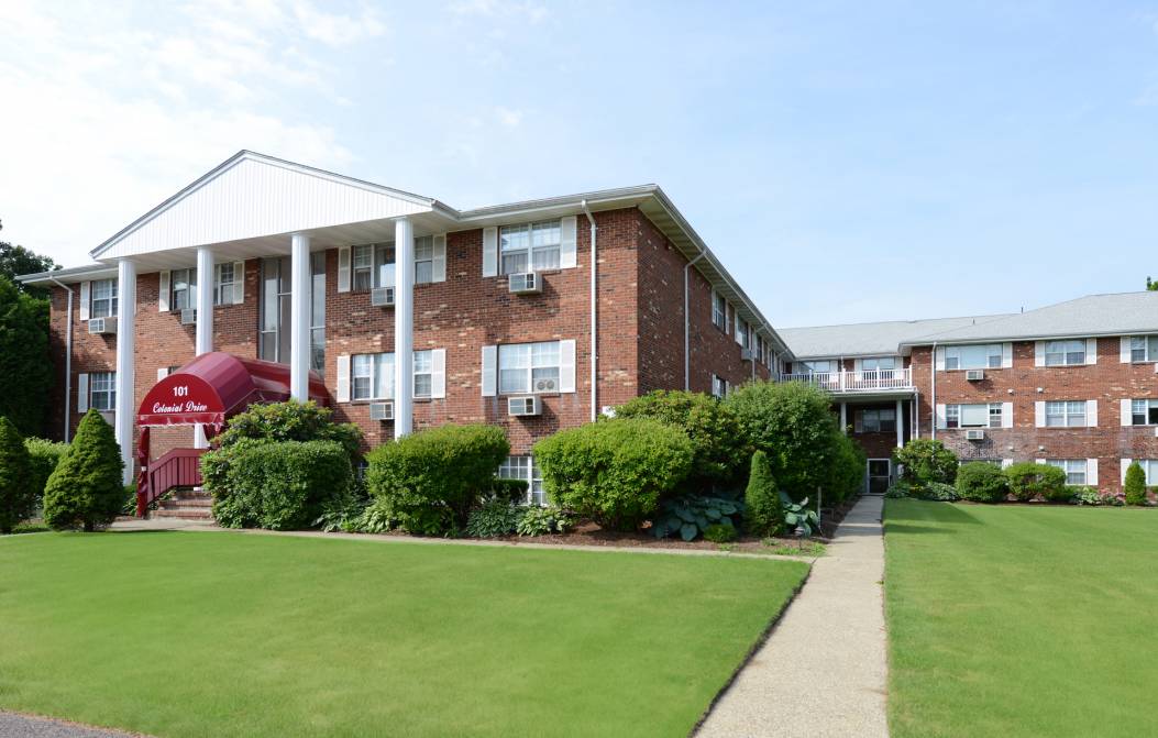 Brick apartment building with manicured lawn.